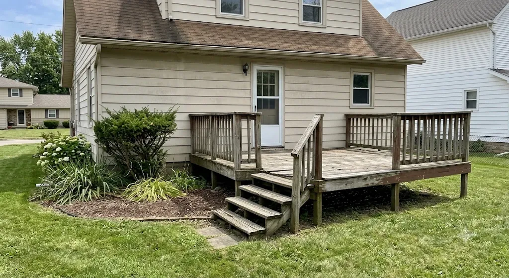 Weathered gray wood deck with worn railing behind a Northeast Ohio home, before rebuild